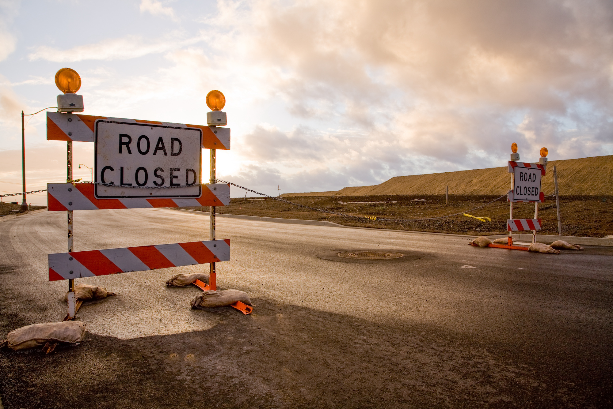 Closed road signs on an empty and deserted road with bleak sky