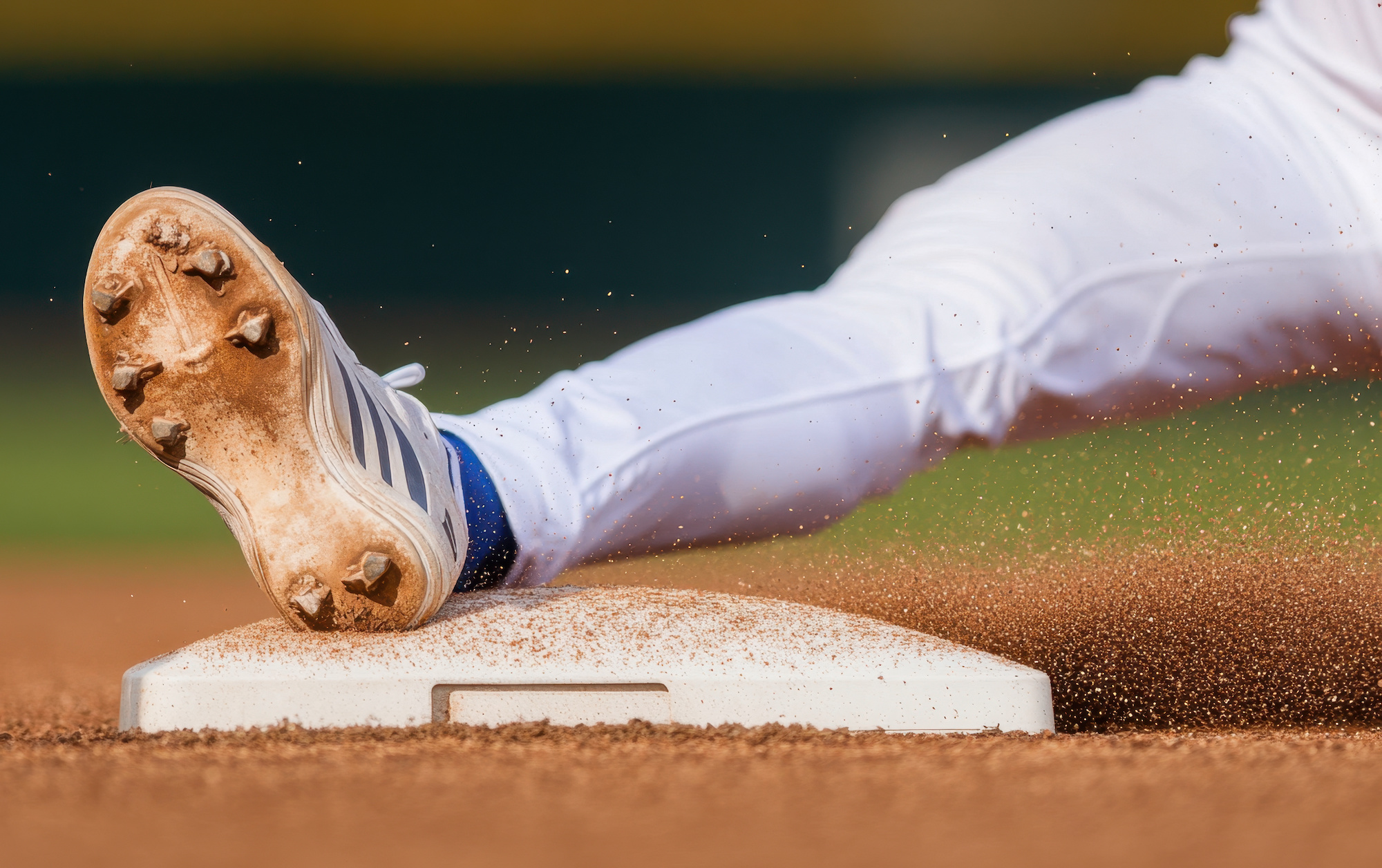 baseball player sliding feet first into base, kicking up dirt and showcasing athleticism. focus is on player foot and base, capturing intensity of game